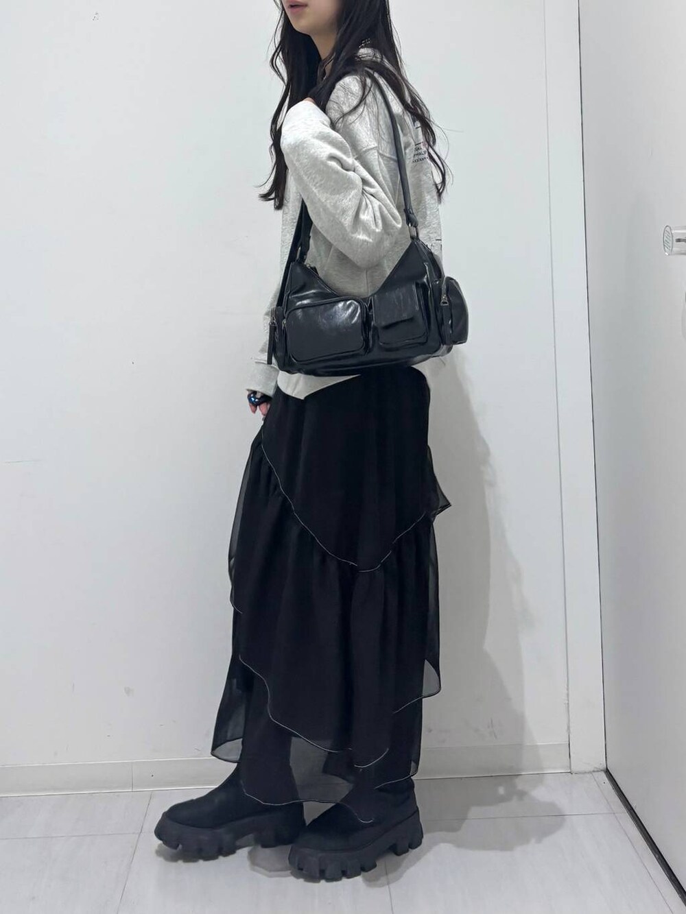 ブラック系のショルダーバッグ、グレー系のスウェット、ブラック系のスカートを着用したレディースの冬コーディネートの2枚目の写真