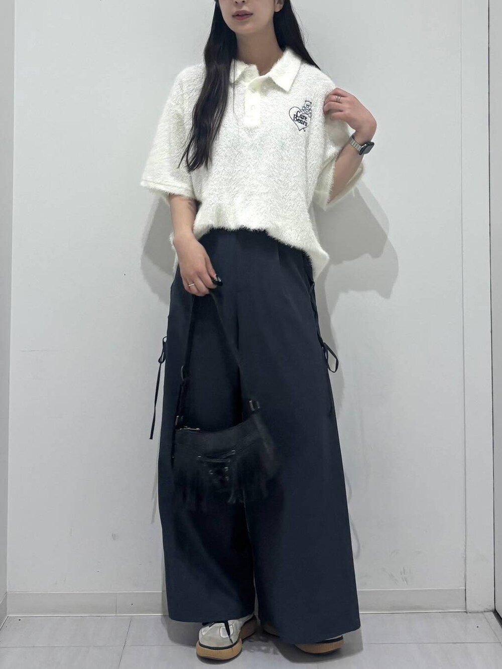 ブラック系のショルダーバッグ、グレー系のスラックス、ホワイト系のポロシャツを着用したレディースの春コーディネートの8枚目の写真