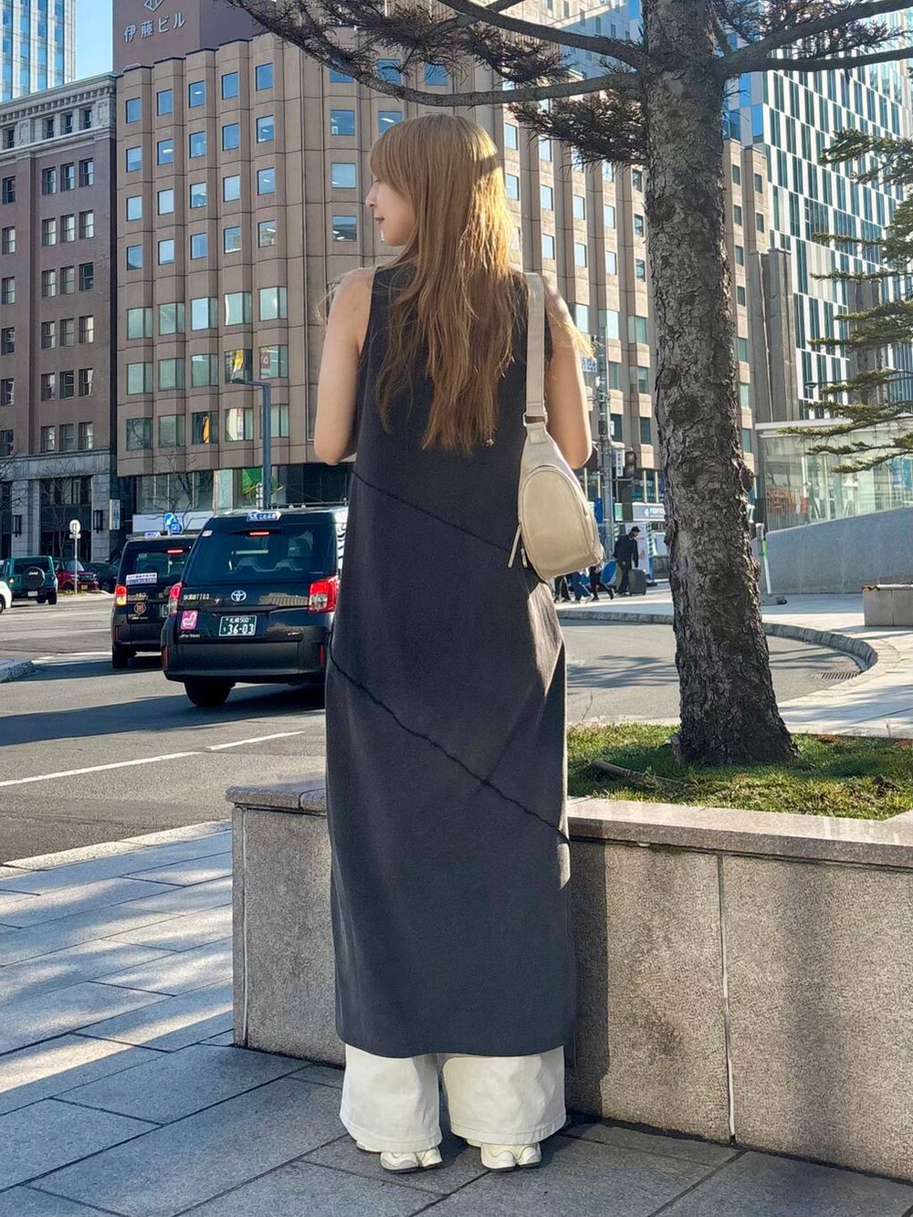 グレー系のデニムパンツ、ホワイト系のショルダーバッグ、ブラック系のワンピースを着用したレディースの春コーディネートの5枚目の写真