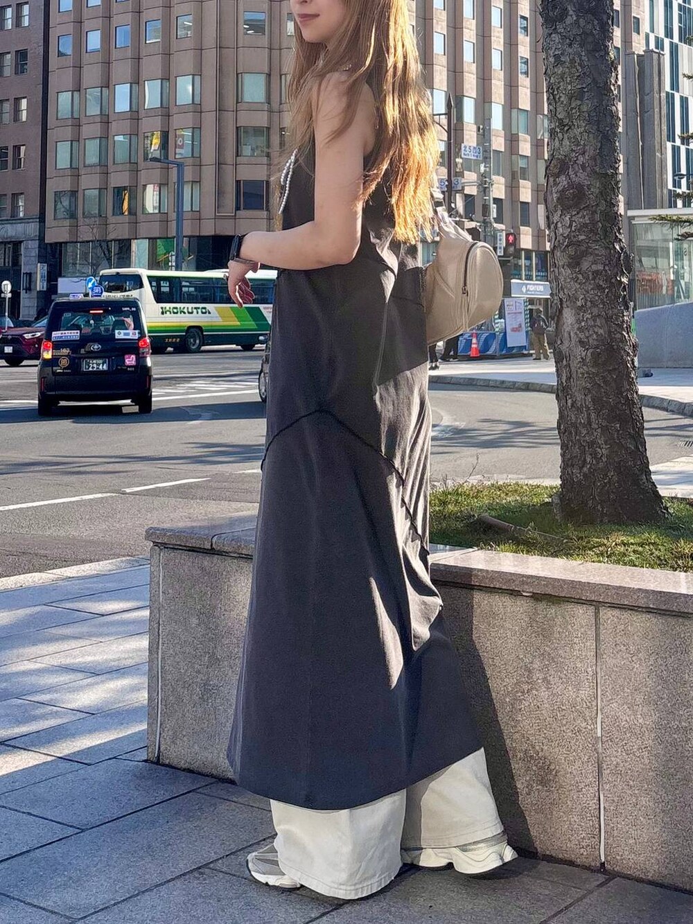 グレー系のデニムパンツ、ホワイト系のショルダーバッグ、ブラック系のワンピースを着用したレディースの春コーディネートの4枚目の写真