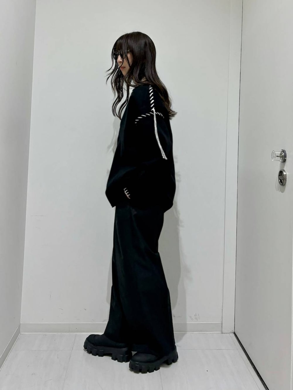 ホワイト系のタンクトップ、ブラック系のブーツ、ブラック系のカーディガン/ボレロを着用したレディースの秋コーディネートの3枚目の写真