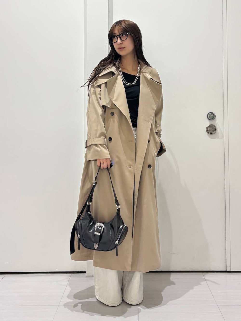 グレー系のデニムパンツ、ベージュ系のトレンチコート、ブラック系のショルダーバッグを着用したレディースの春コーディネートの2枚目の写真