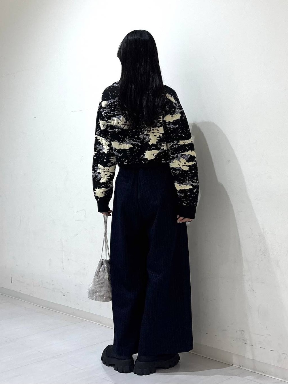 シルバー系のショルダーバッグ、ブルー系のスラックス、ブラック系のニット/セーターを着用したレディースの冬コーディネートの3枚目の写真