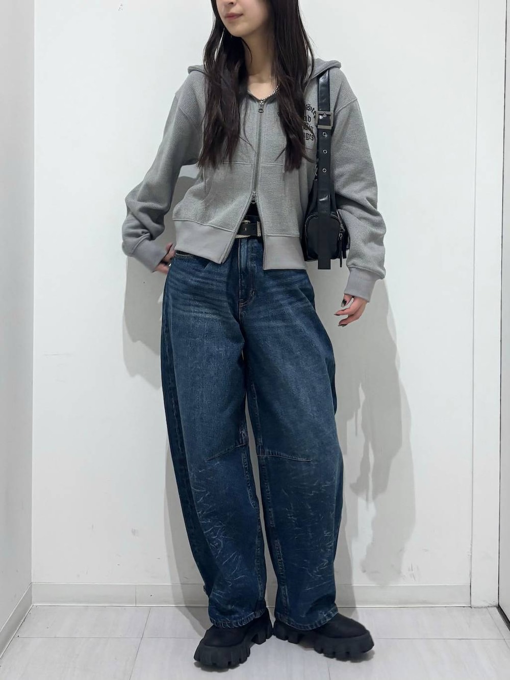 ブルー系のデニムパンツ、グレー系のパーカー、ブラック系のベルトを着用したレディースの冬コーディネートの2枚目の写真