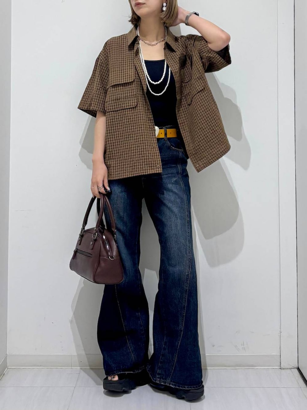 ブラウン系のショルダーバッグ、ブルー系のデニムパンツ、ブラウン系のシャツ/ブラウスを着用したレディースの夏コーディネートの2枚目の写真