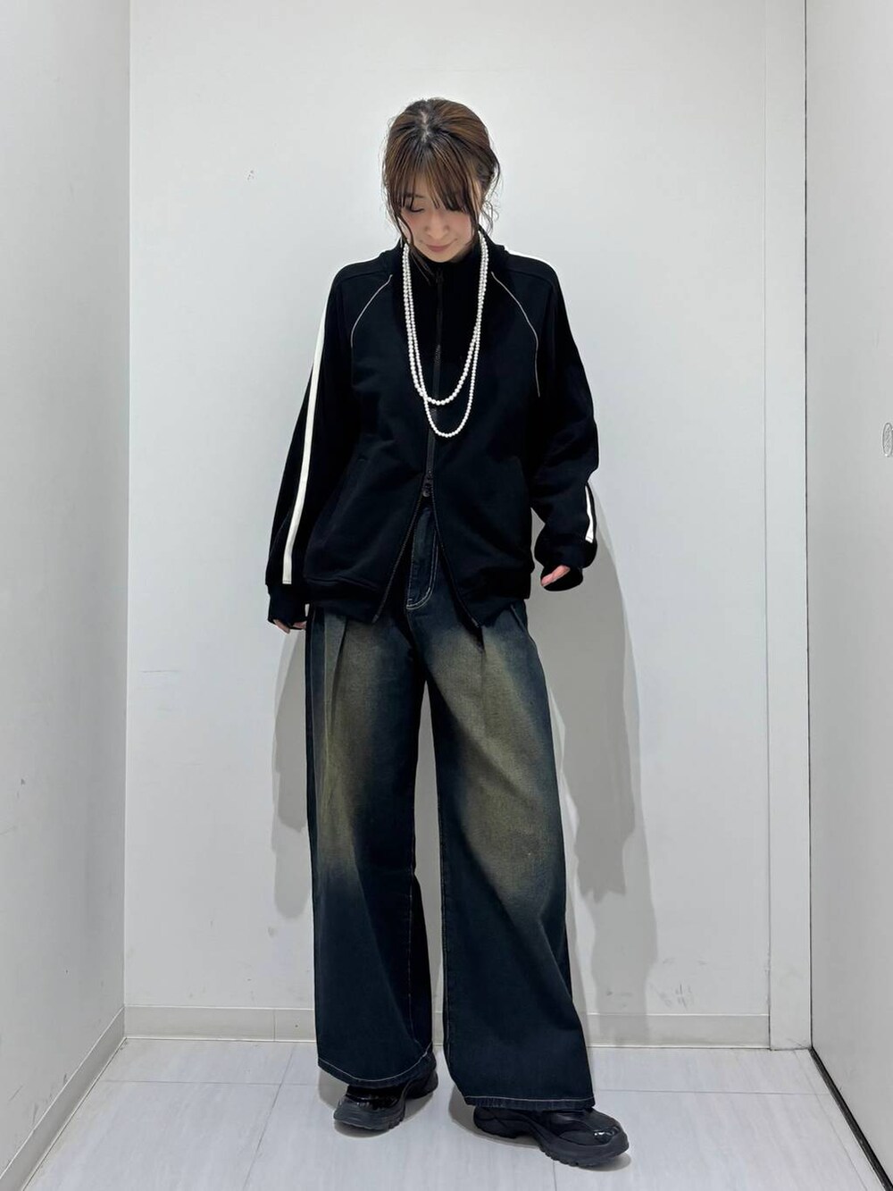 ブルー系のデニムパンツ、ブラック系のスニーカー、ブラック系のスウェットを着用したレディースの春コーディネートの2枚目の写真