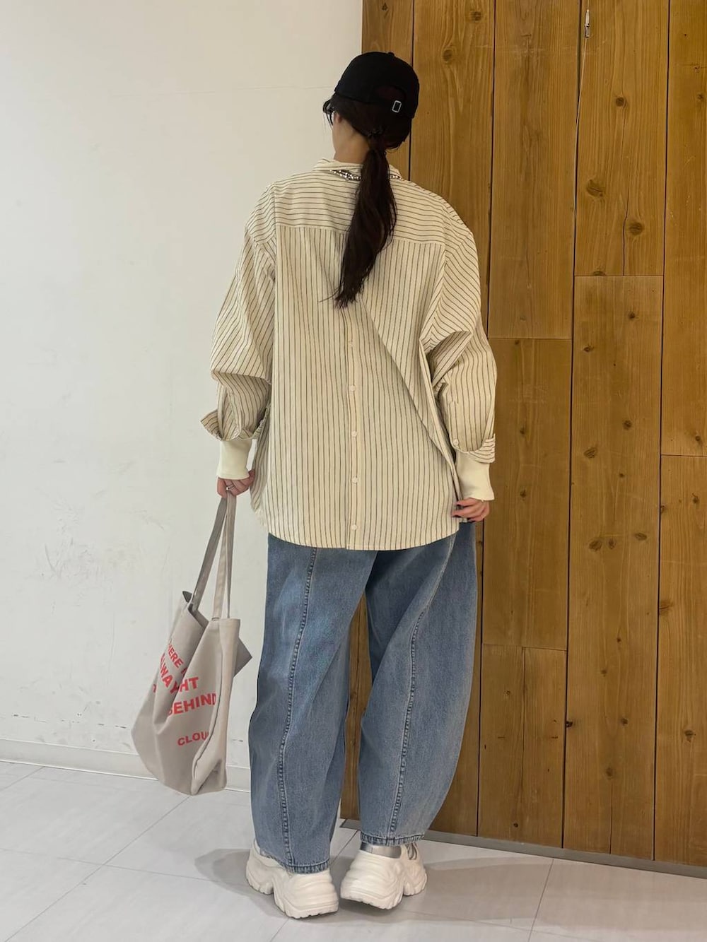 ホワイト系のスニーカー、ベージュ系のトートバッグ、ブルー系のデニムパンツを着用したレディースの冬コーディネートの3枚目の写真