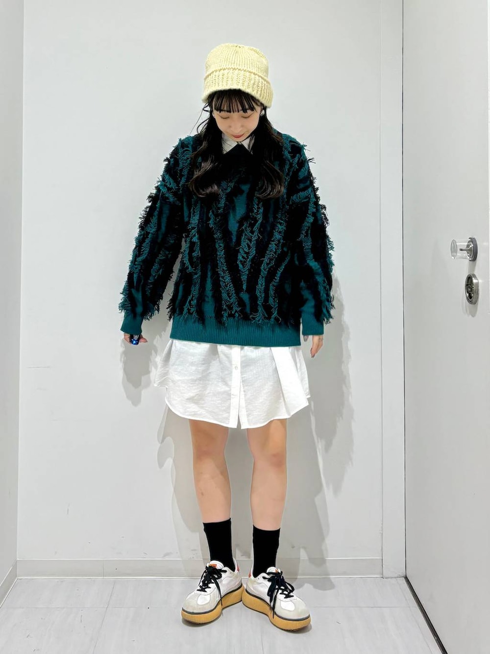 グリーン系のニット/セーター、ブラック系のその他パンツ、ホワイト系のシャツ/ブラウスを着用したレディースの秋コーディネートの2枚目の写真