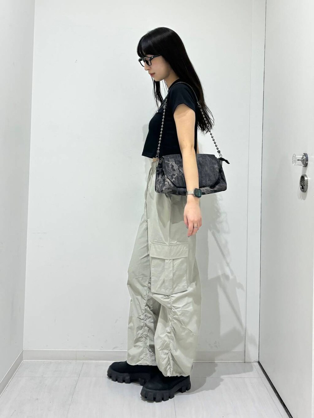 ブラック系のショルダーバッグ、ブラック系のTシャツ/カットソー、ブラック系のブーツを着用したレディースの春コーディネートの4枚目の写真