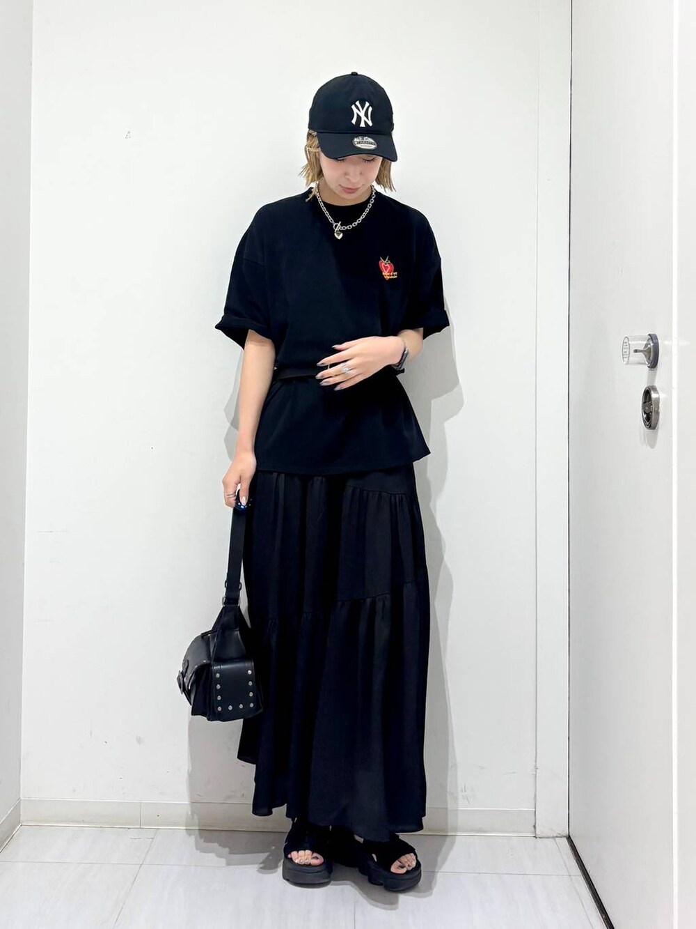 ブラック系のTシャツ/カットソー、ブラック系のスカート、ブラック系のショルダーバッグを着用したレディースの夏コーディネートの2枚目の写真