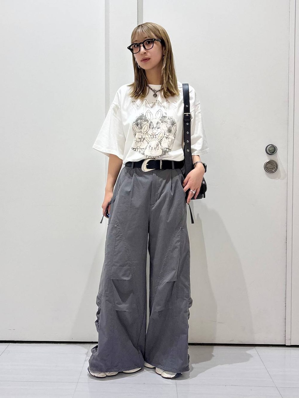 ブラック系のショルダーバッグ、グレー系のカーゴパンツ、ホワイト系のTシャツ/カットソーを着用したレディースの春コーディネートの7枚目の写真