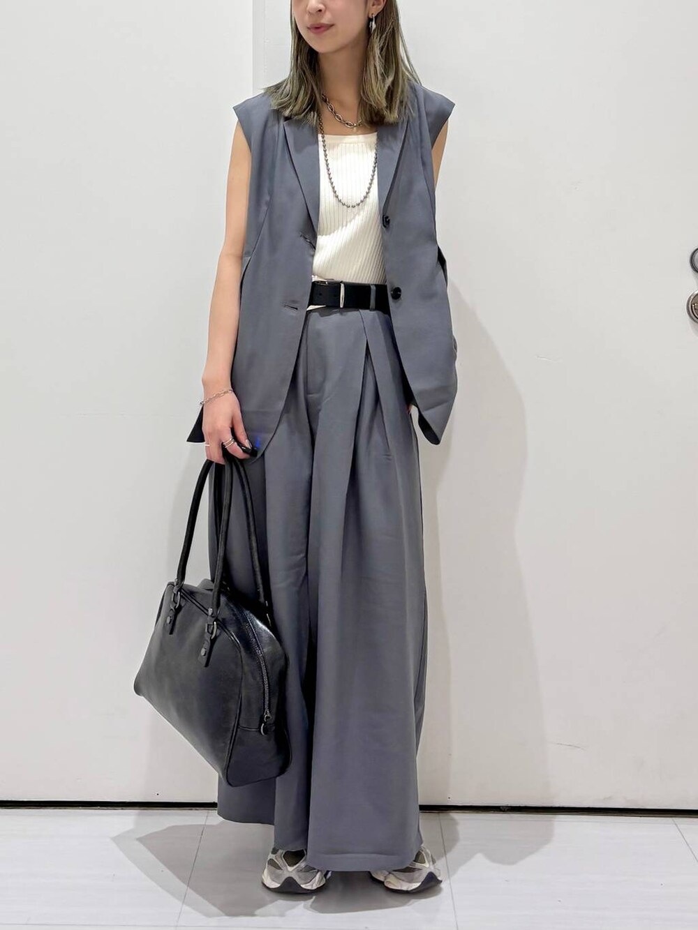 ブラック系のボストンバッグ、ホワイト系のタンクトップ、グレー系のスラックスを着用したレディースの春コーディネートの4枚目の写真