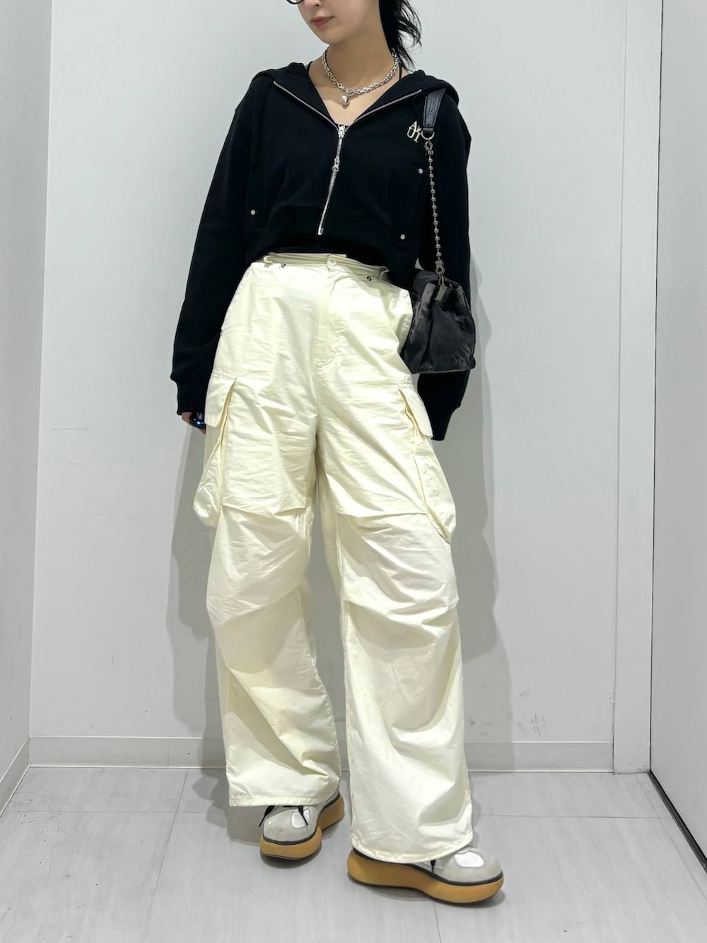 ブラック系のパーカー、ブラック系のショルダーバッグ、ホワイト系のカーゴパンツを着用したレディースの春コーディネートの2枚目の写真