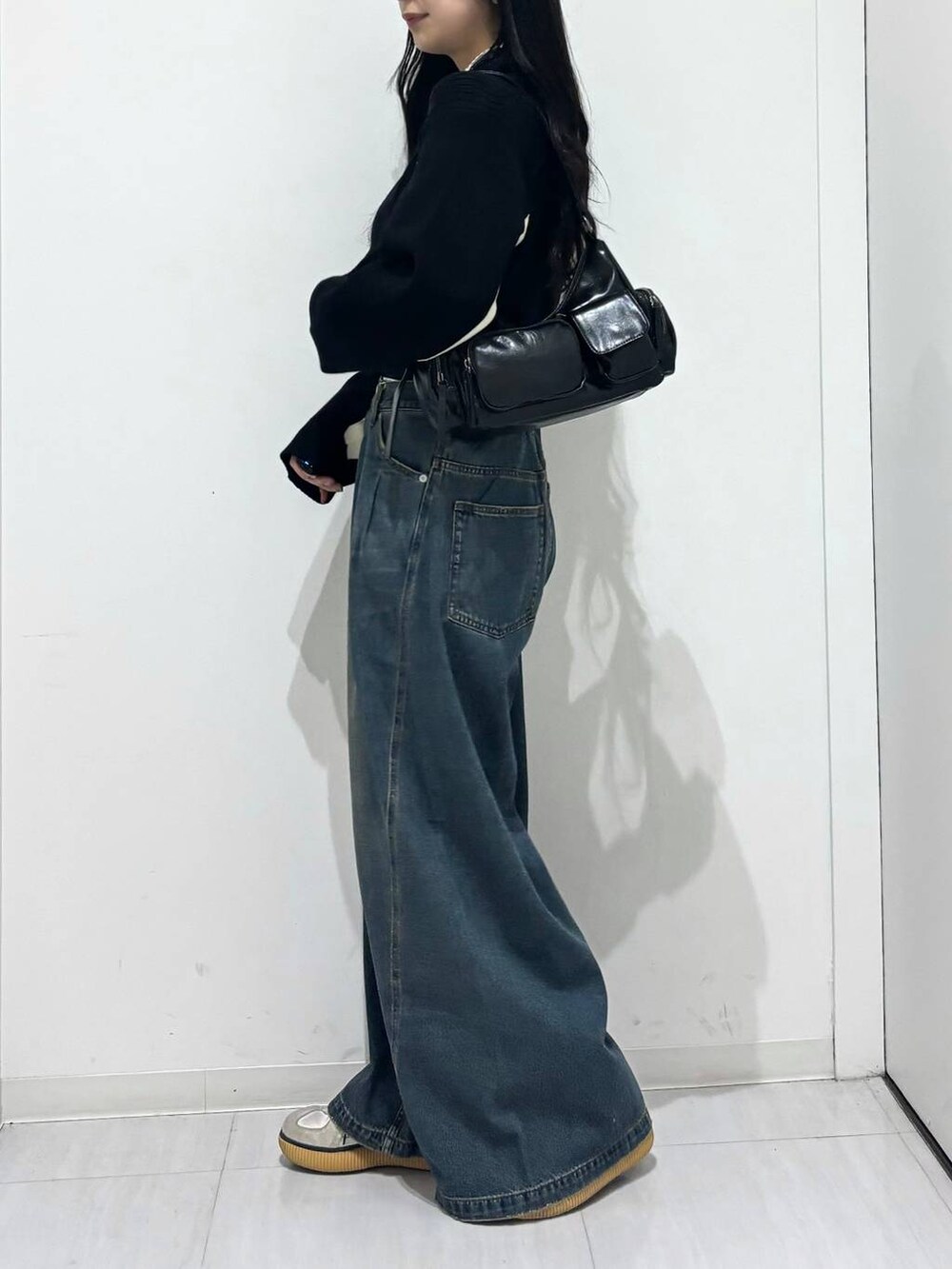 ブルー系のデニムパンツ、ブラック系のショルダーバッグ、ブラック系のニット/セーターを着用したレディースの秋コーディネートの3枚目の写真