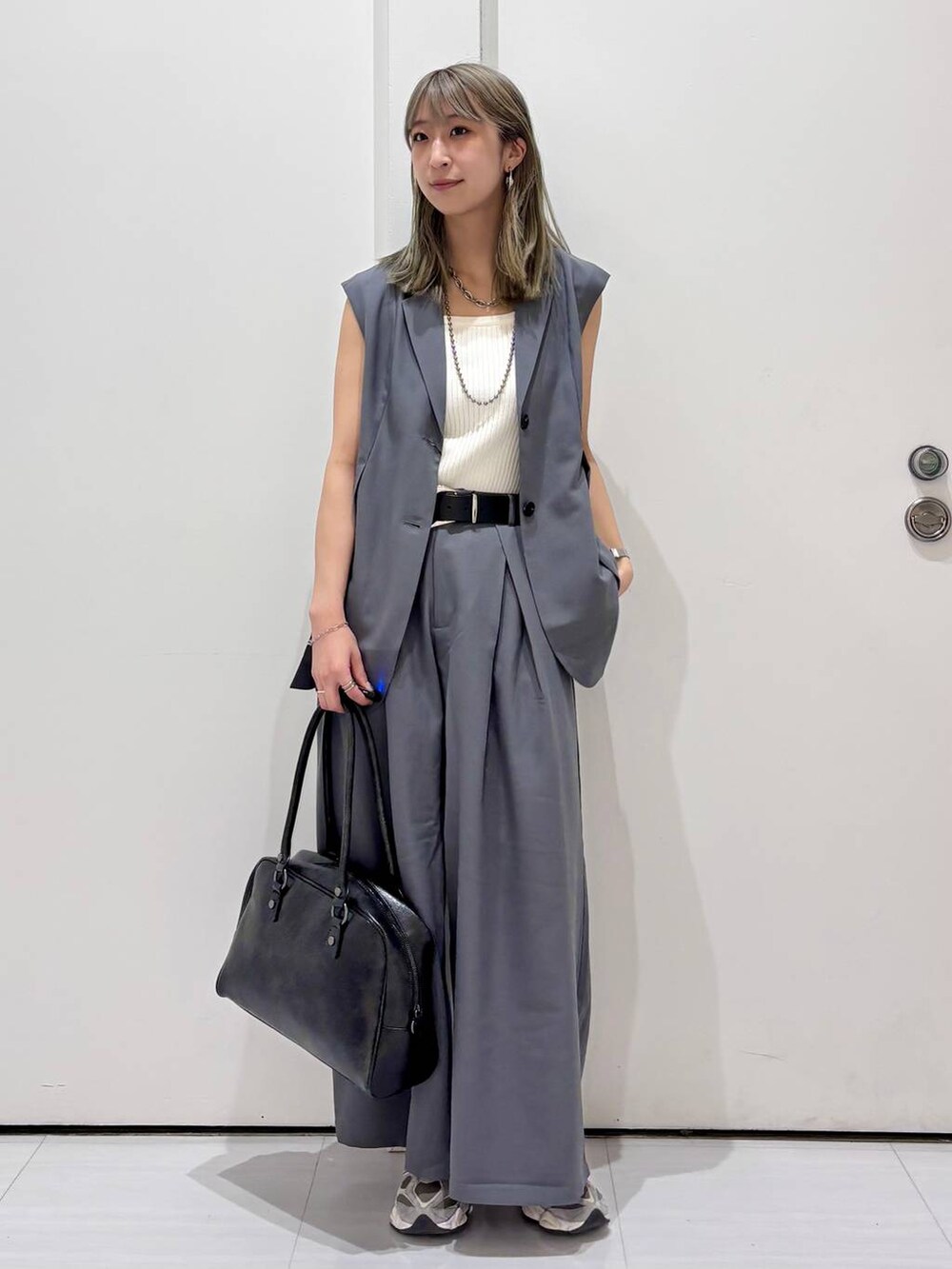 ブラック系のボストンバッグ、ホワイト系のタンクトップ、グレー系のスラックスを着用したレディースの春コーディネートの8枚目の写真