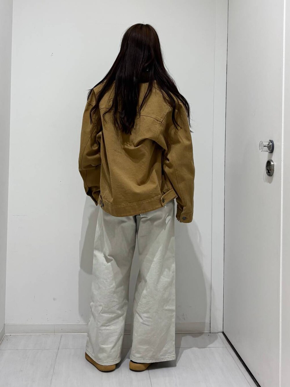 グレー系のデニムパンツ、ベージュ系のカバーオールを着用したレディースの春コーディネートの4枚目の写真