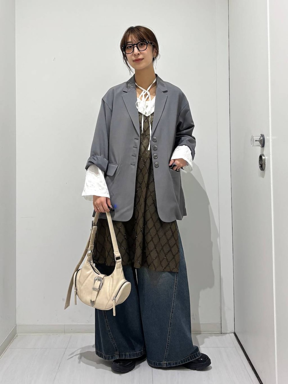 ブルー系のデニムパンツ、ブラック系のスニーカー、ホワイト系のショルダーバッグを着用したレディースの春コーディネートの8枚目の写真