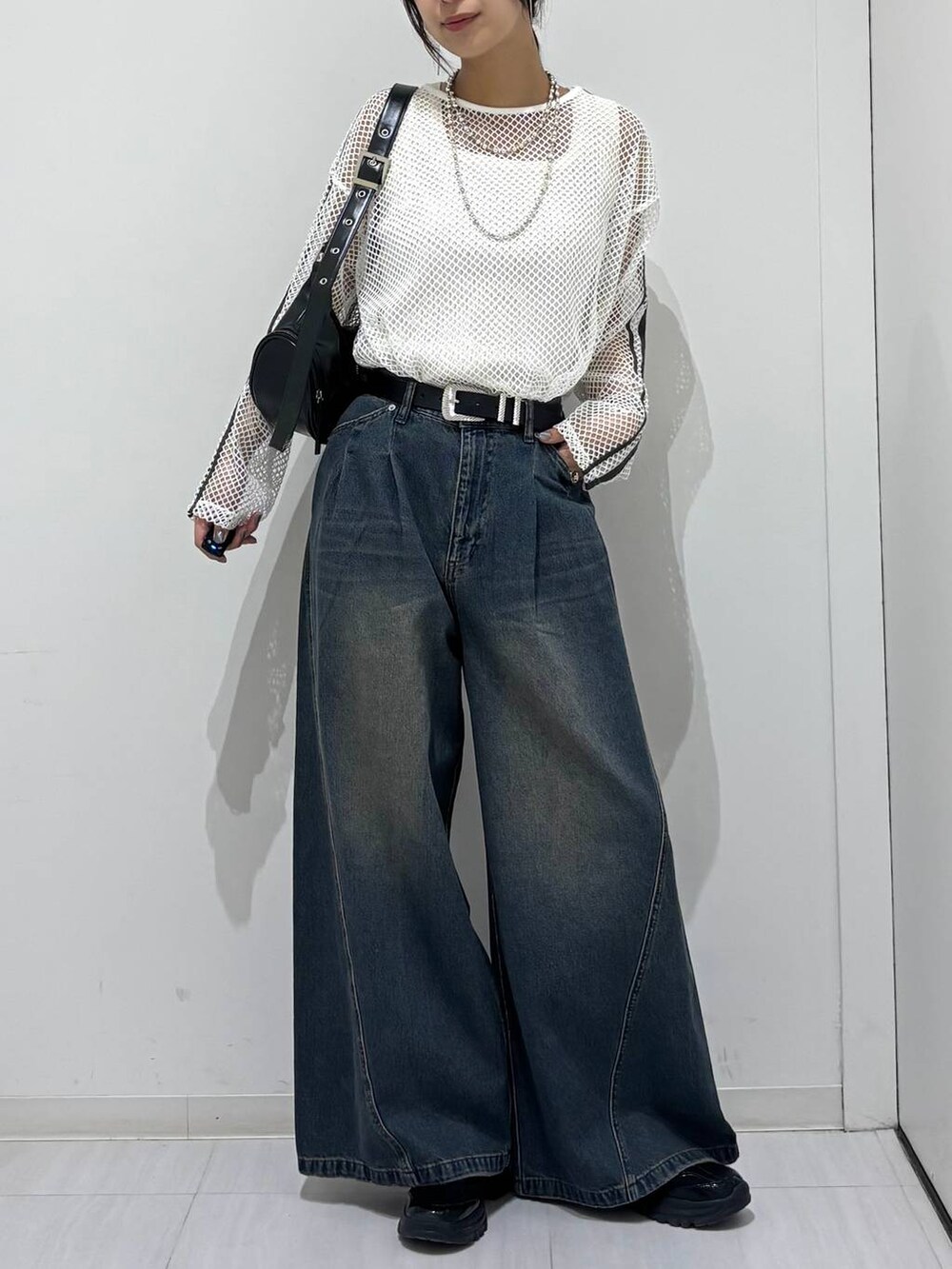 ブルー系のデニムパンツ、ブラック系のスニーカー、ホワイト系のTシャツ/カットソーを着用したレディースの春コーディネートの2枚目の写真