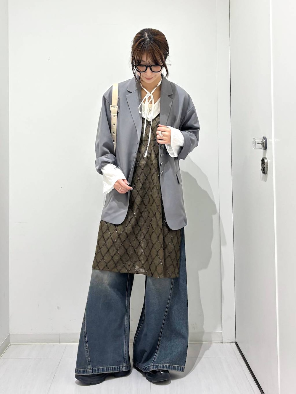 ブルー系のデニムパンツ、ブラック系のスニーカー、ホワイト系のショルダーバッグを着用したレディースの春コーディネートの7枚目の写真