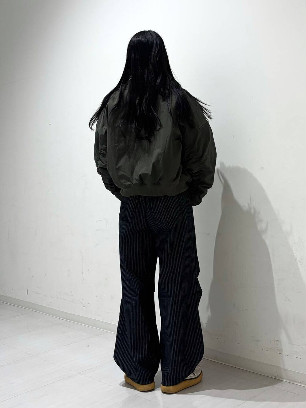 ブラック系のデニムパンツ、グリーン系のブルゾン、ブラック系のスウェットを着用したレディースの秋コーディネートの4枚目の写真