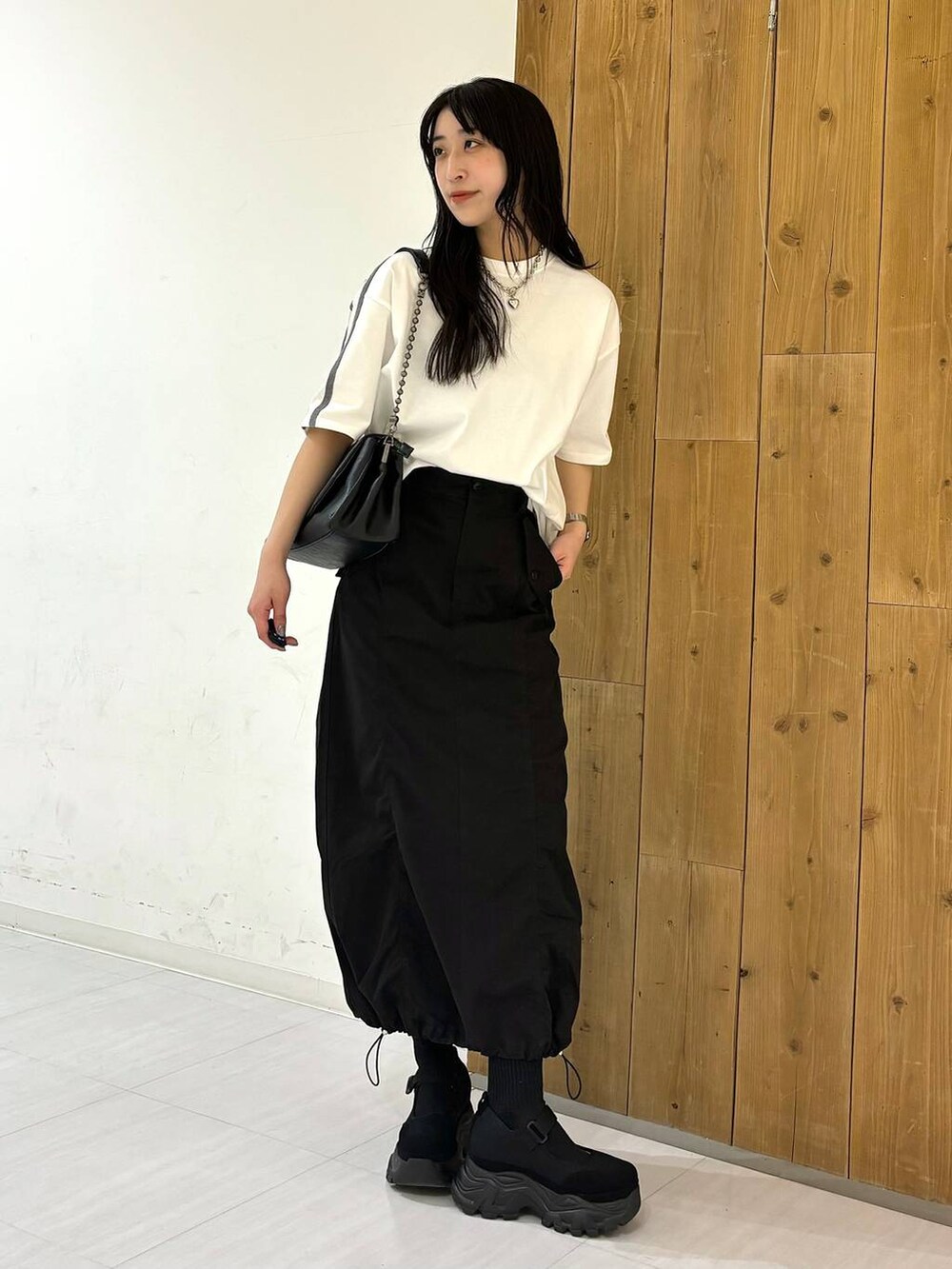 ブラック系のショルダーバッグ、ホワイト系のTシャツ/カットソー、ブラック系のスニーカーを着用したレディースの春コーディネートの2枚目の写真