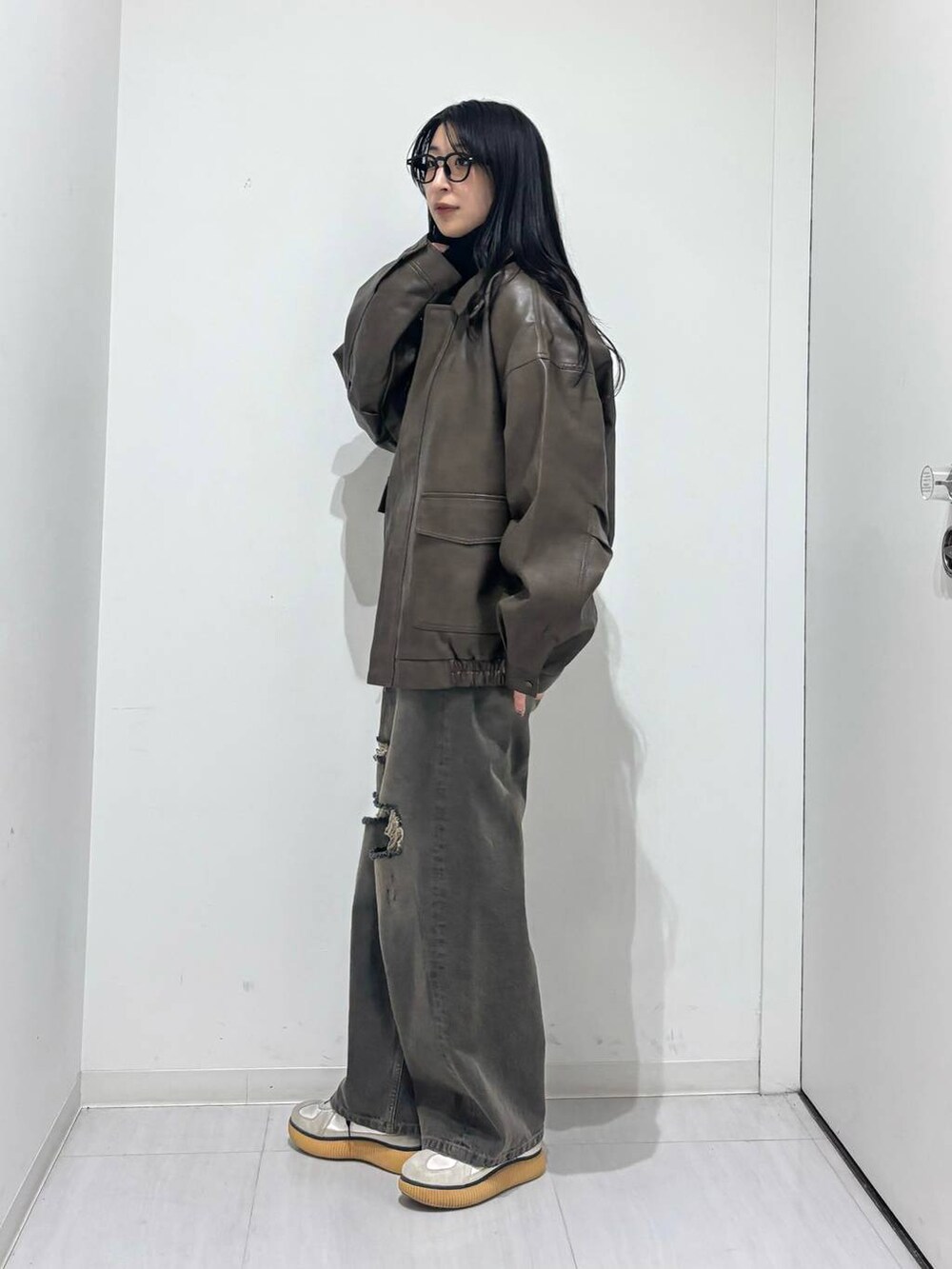 ブラウン系のブルゾン、ブラック系のデニムパンツ、ブラック系のニット/セーターを着用したレディースの秋コーディネートの2枚目の写真