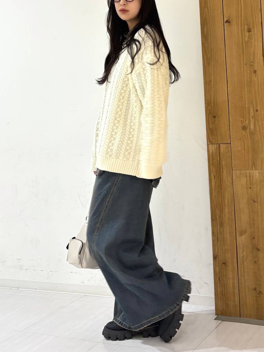 ブルー系のデニムパンツ、ホワイト系のショルダーバッグ、ホワイト系のニット/セーターを着用したレディースの冬コーディネートの2枚目の写真