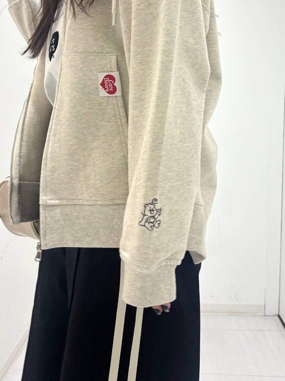 ホワイト系のショルダーバッグ、ブラック系のスラックス、ベージュ系のパーカーを着用したレディースの春コーディネートの5枚目の写真