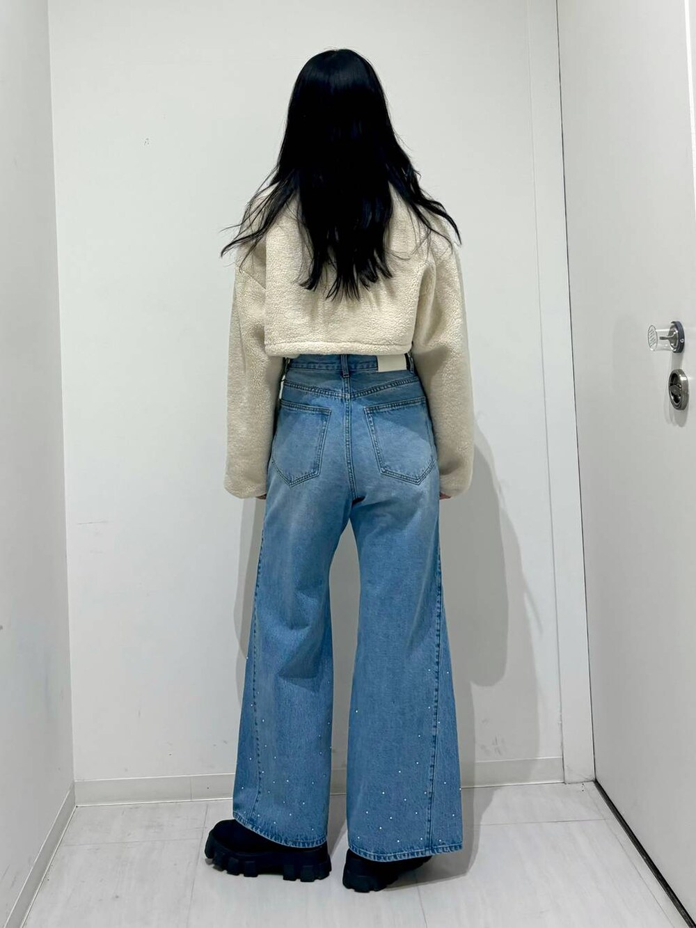 ブラック系のブーツ、ホワイト系のその他アウター、ブルー系のデニムパンツを着用したレディースの冬コーディネートの3枚目の写真