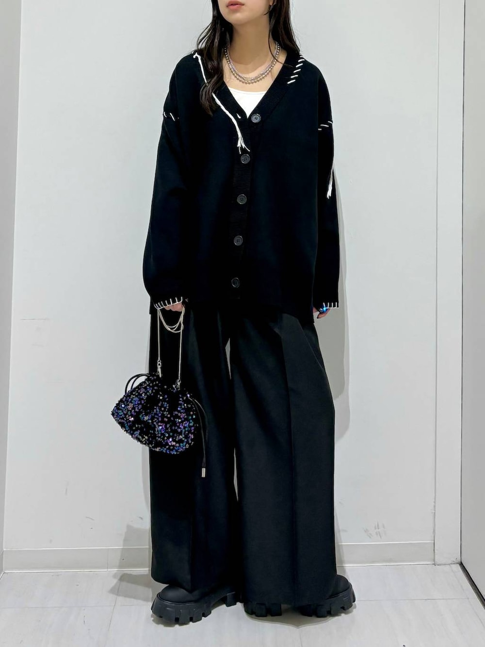 ホワイト系のタンクトップ、ブラック系のブーツ、ブラック系のカーディガン/ボレロを着用したレディースの秋コーディネートの2枚目の写真