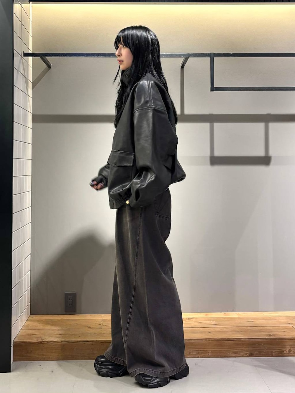 ブラック系のデニムパンツ、ブラック系のブルゾン、ブラック系のブーツを着用したレディースの秋コーディネートの4枚目の写真