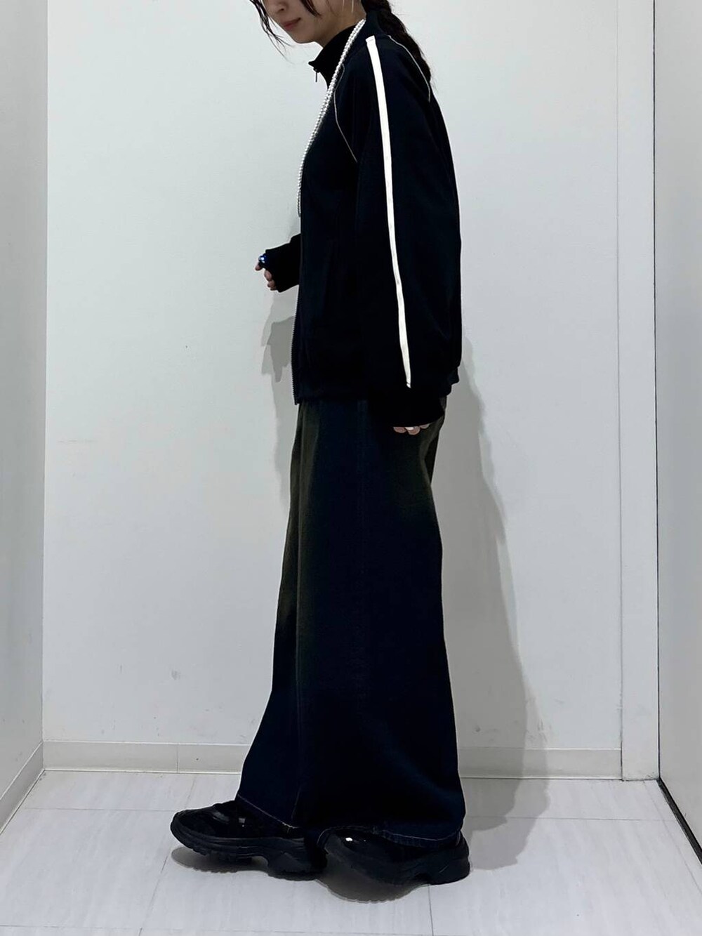 ブルー系のデニムパンツ、ブラック系のスニーカー、ブラック系のスウェットを着用したレディースの春コーディネートの3枚目の写真