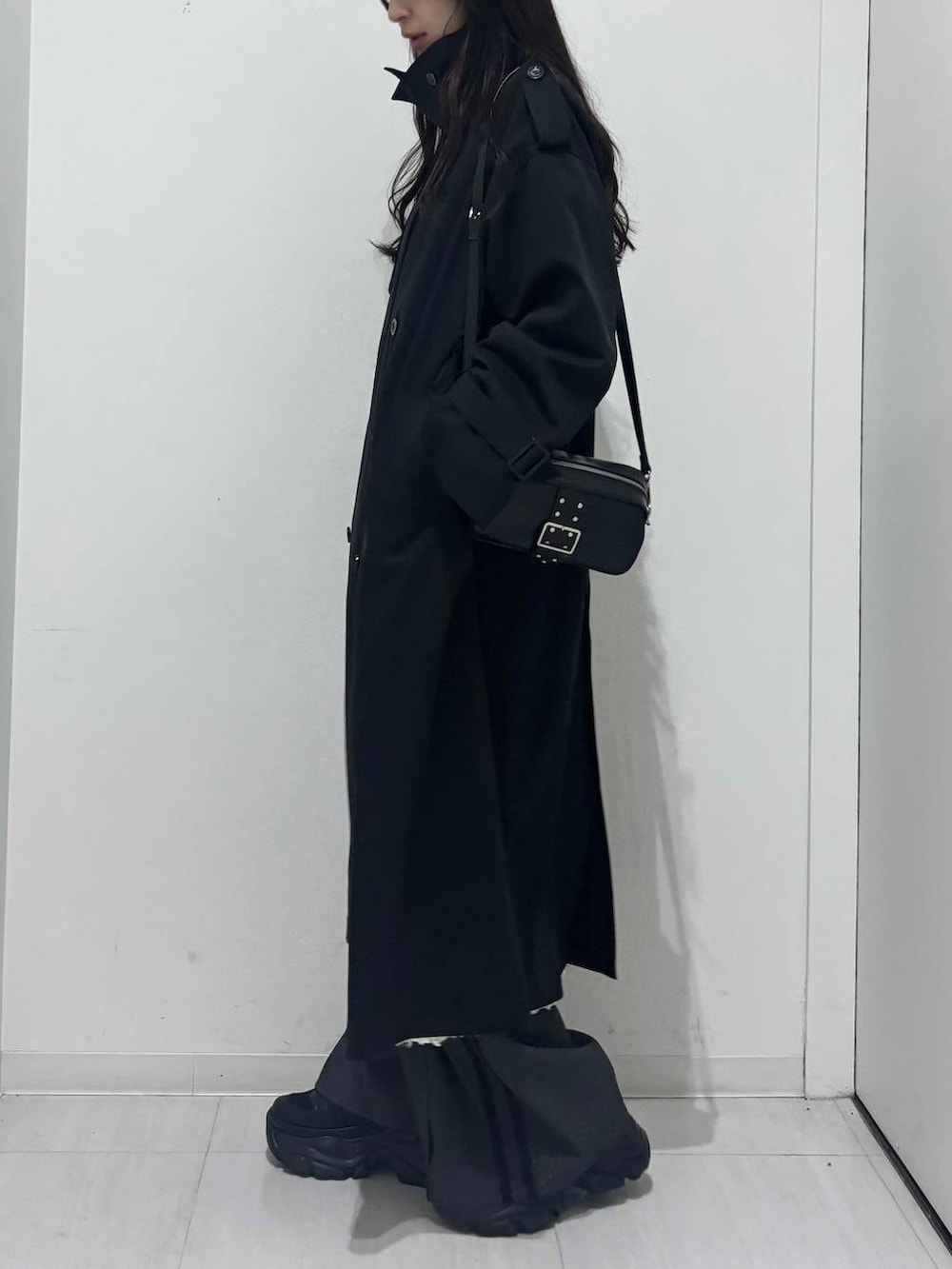 ブラック系のスニーカー、ブラック系のトレンチコート、ホワイト系のワンピースを着用したレディースの冬コーディネートの2枚目の写真