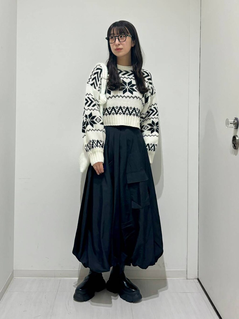 ブラック系のブーツ、ホワイト系のニット/セーター、ブラック系のスカートを着用したレディースの冬コーディネートの4枚目の写真