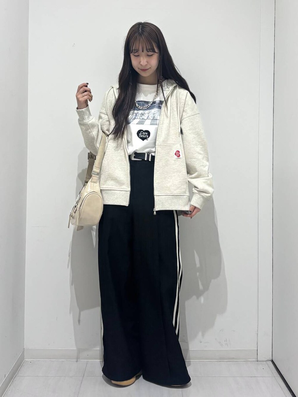 ホワイト系のショルダーバッグ、ブラック系のスラックス、ベージュ系のパーカーを着用したレディースの春コーディネートの6枚目の写真
