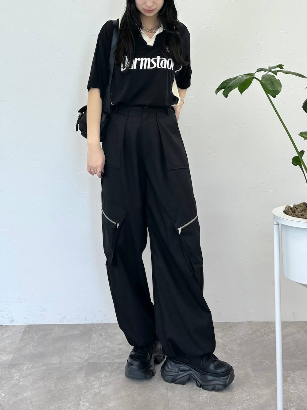 ブラック系のショルダーバッグ、ブラック系のスニーカー、ブラック系のスラックスを着用したレディースの春コーディネートの2枚目の写真