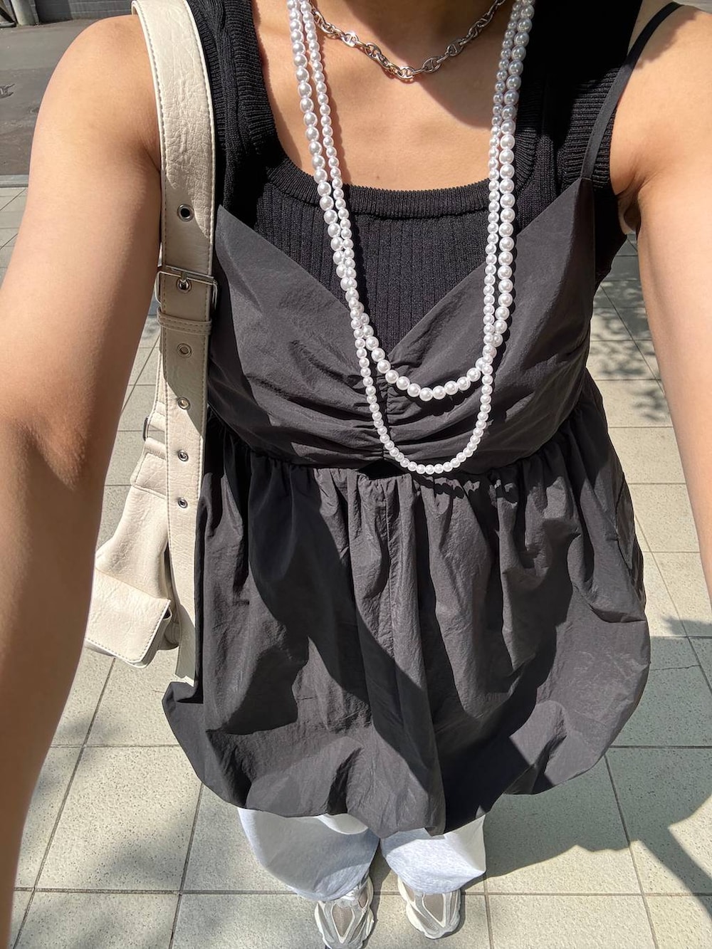 ブラック系のタンクトップ、ホワイト系のショルダーバッグ、グレー系のスウェットパンツを着用したレディースの夏コーディネートの6枚目の写真