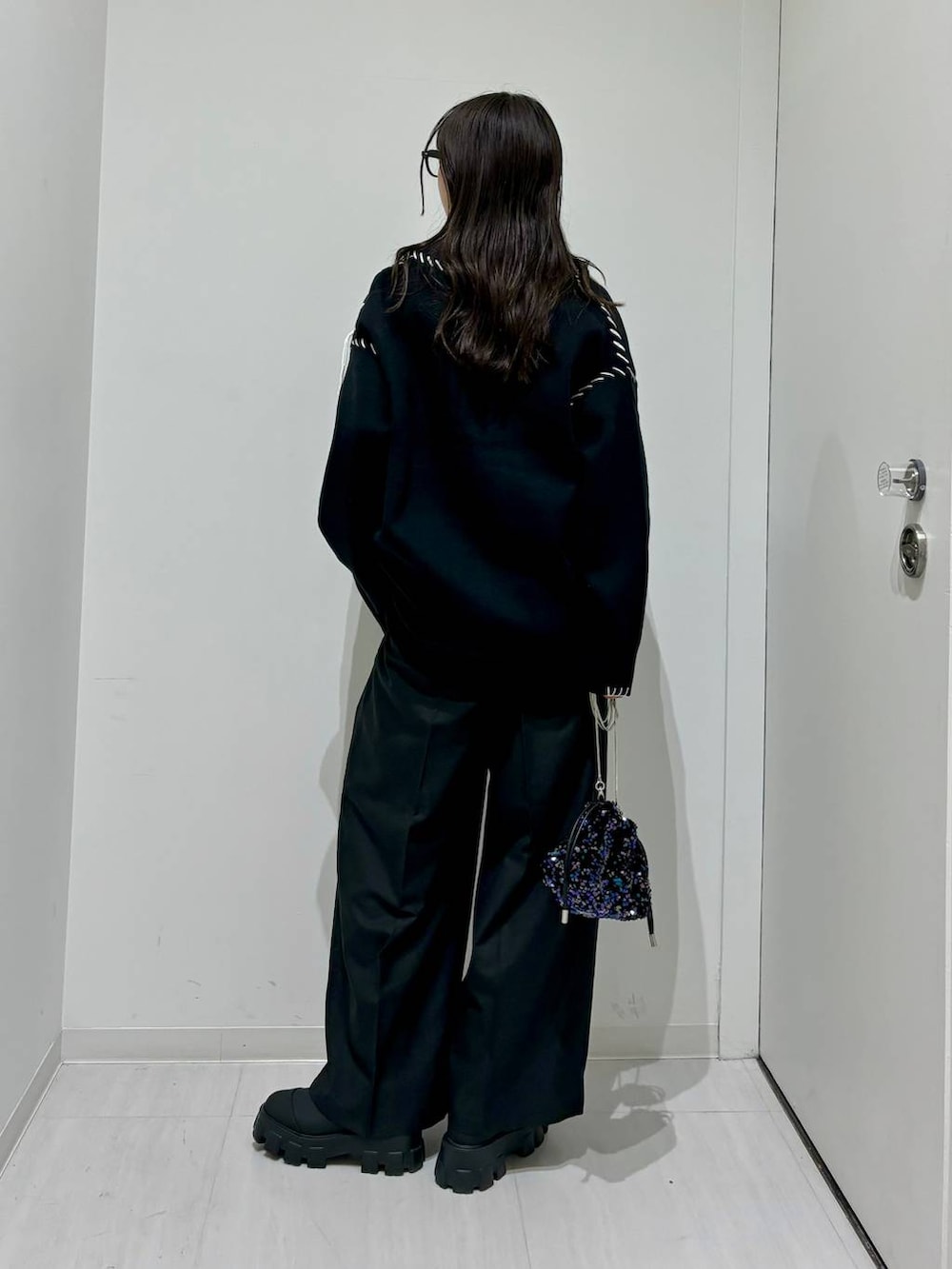 ホワイト系のタンクトップ、ブラック系のブーツ、ブラック系のカーディガン/ボレロを着用したレディースの秋コーディネートの4枚目の写真