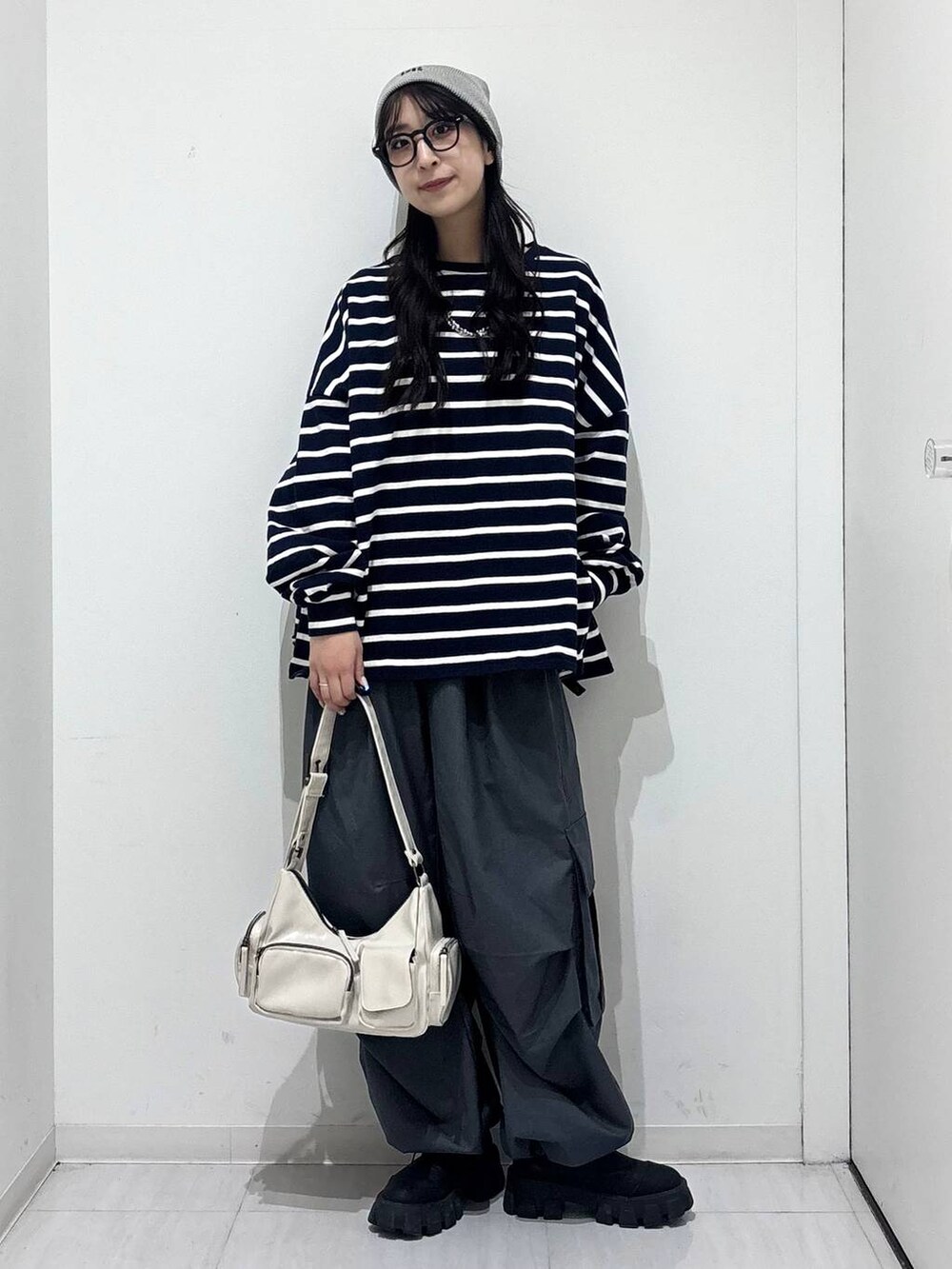 ホワイト系のショルダーバッグ、ブルー系のTシャツ/カットソー、グレー系のカーゴパンツを着用したレディースの冬コーディネートの2枚目の写真