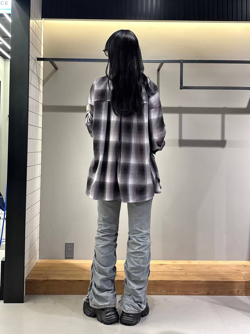 ブラック系のスニーカー、ホワイト系のキャミソール、ブルー系のデニムパンツを着用したレディースの秋コーディネートの4枚目の写真