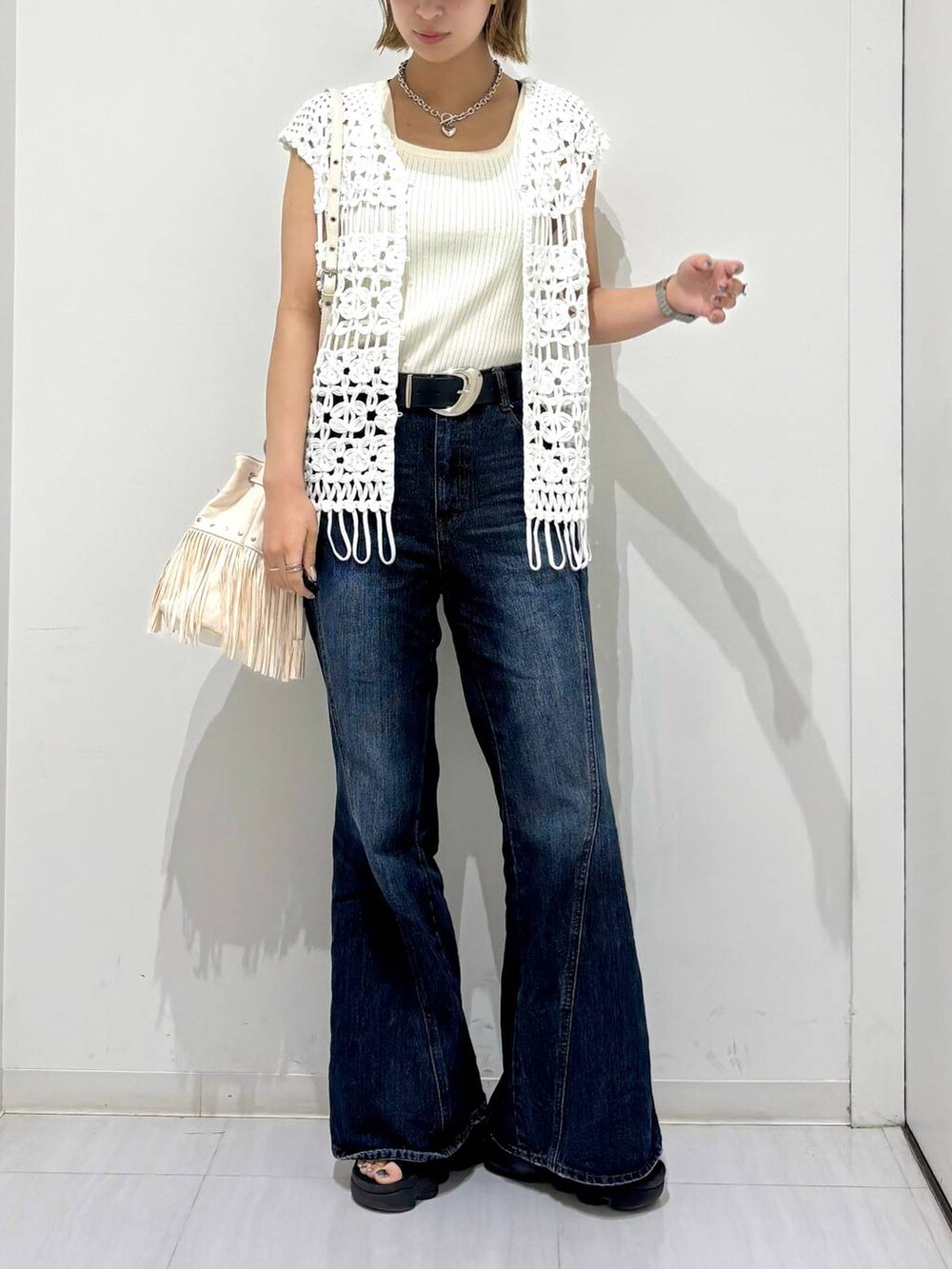 ホワイト系のタンクトップ、ブルー系のデニムパンツ、ホワイト系のベストを着用したレディースの夏コーディネートの3枚目の写真