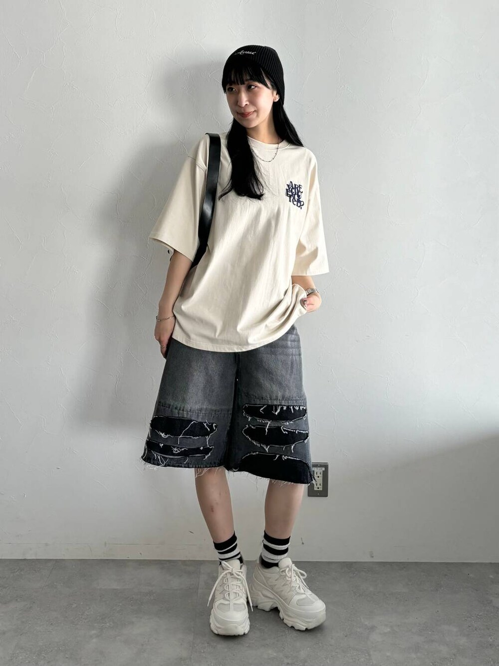 ホワイト系のスニーカー、ブラック系のショルダーバッグ、ブラック系のデニムパンツを着用したレディースの春コーディネートの4枚目の写真