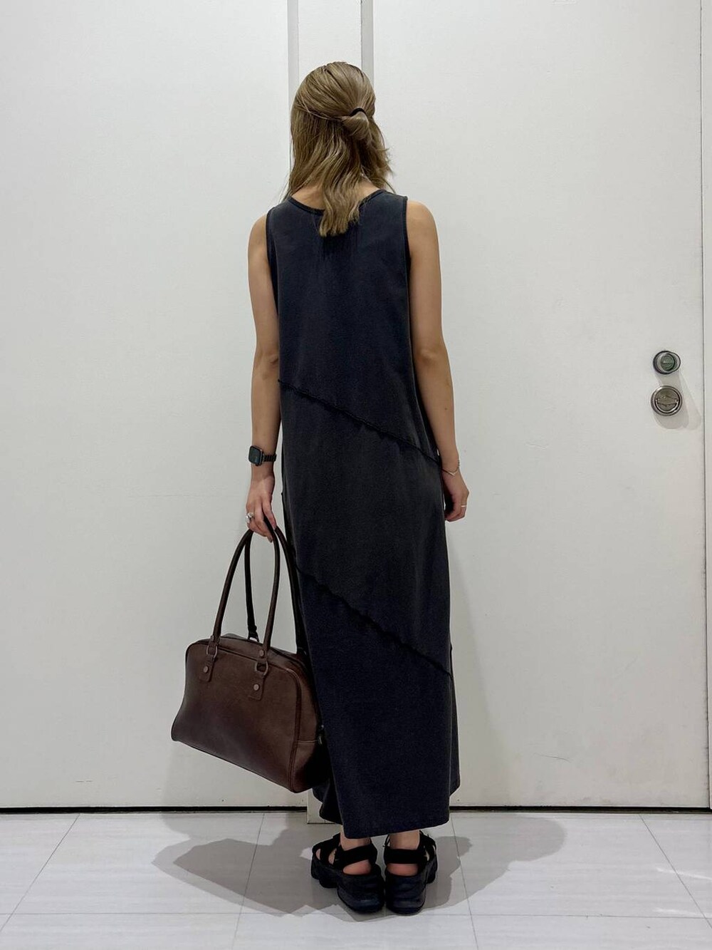 ブラウン系のボストンバッグ、ブラック系のワンピース、ホワイト系のネックレスを着用したレディースの春コーディネートの4枚目の写真