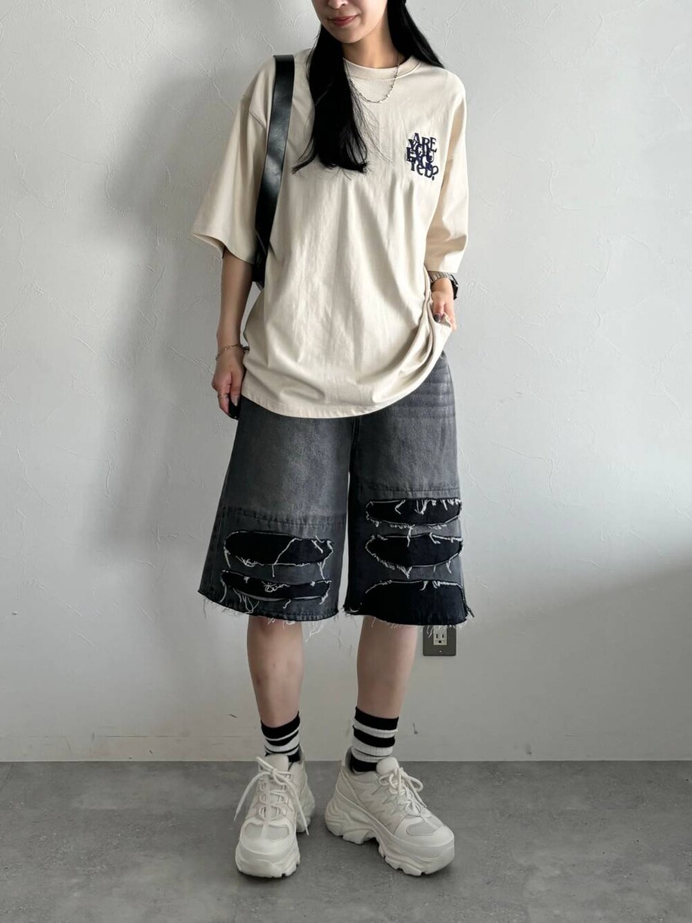 ホワイト系のスニーカー、ブラック系のショルダーバッグ、ブラック系のデニムパンツを着用したレディースの春コーディネートの2枚目の写真