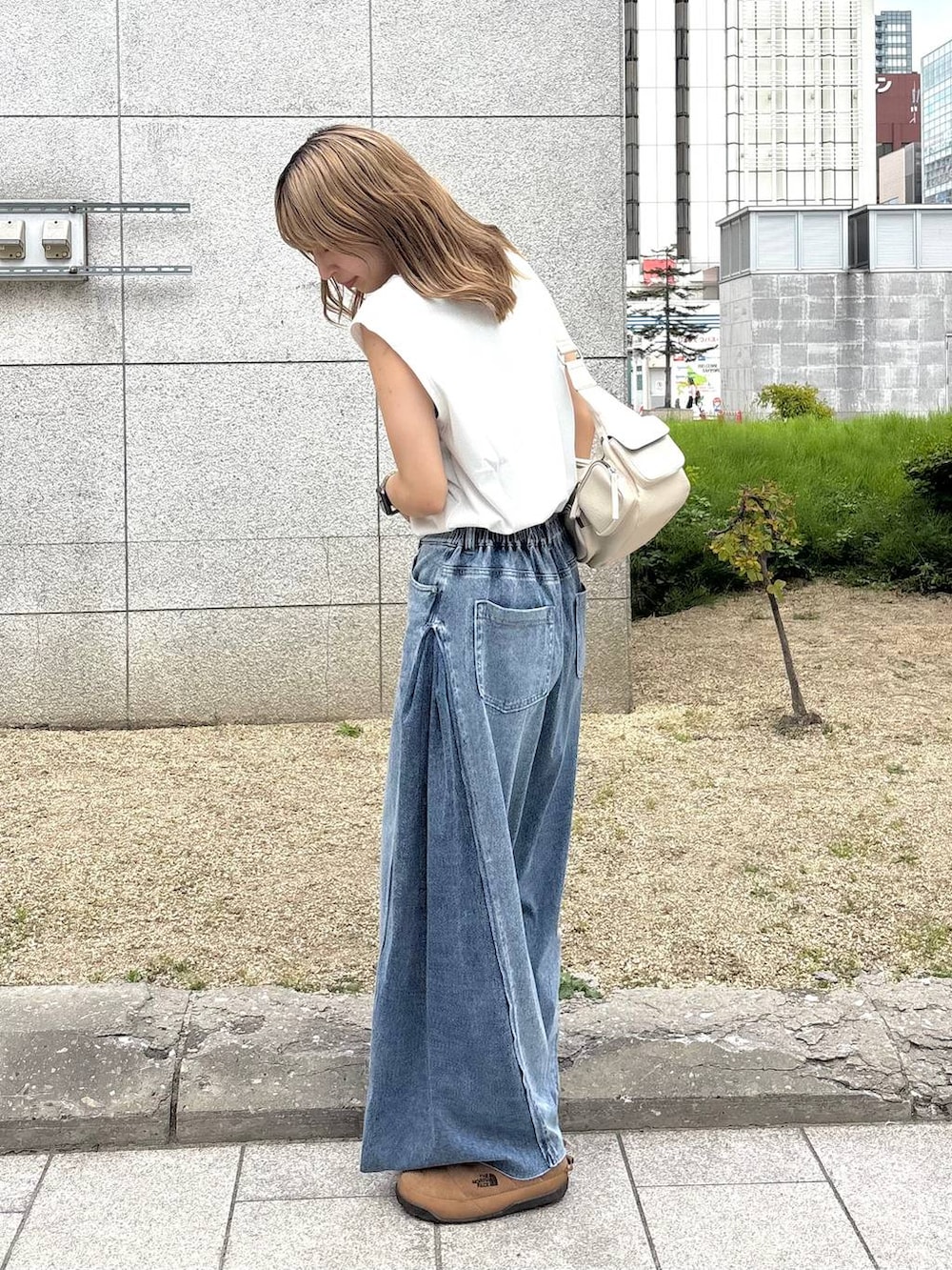 ブルー系のデニムパンツ、ホワイト系のショルダーバッグ、ホワイト系のTシャツ/カットソーを着用したレディースの夏コーディネートの2枚目の写真