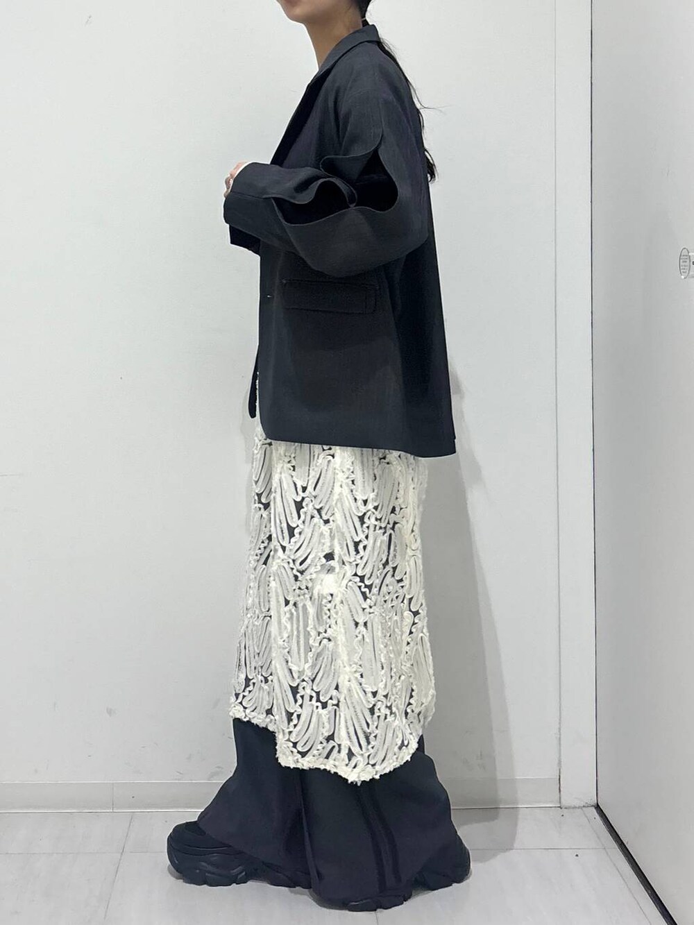 ブラック系のスニーカー、ホワイト系のワンピース、ブラック系のショルダーバッグを着用したレディースの冬コーディネートの3枚目の写真