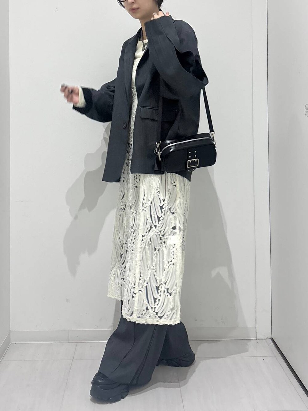 ブラック系のスニーカー、ホワイト系のワンピース、ブラック系のショルダーバッグを着用したレディースの冬コーディネートの4枚目の写真