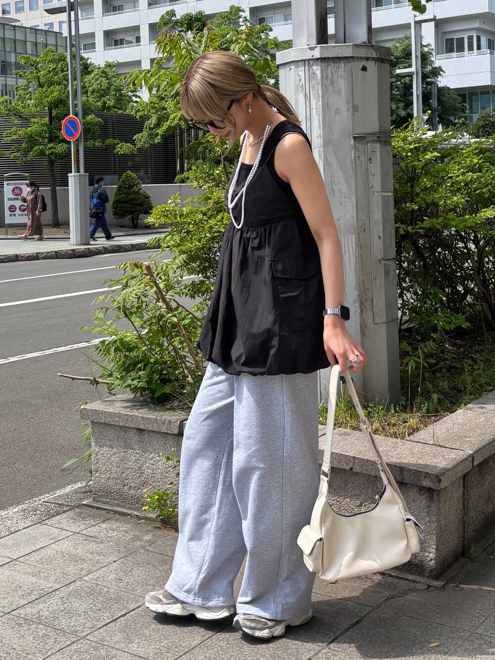 ブラック系のタンクトップ、ホワイト系のショルダーバッグ、グレー系のスウェットパンツを着用したレディースの夏コーディネートの3枚目の写真