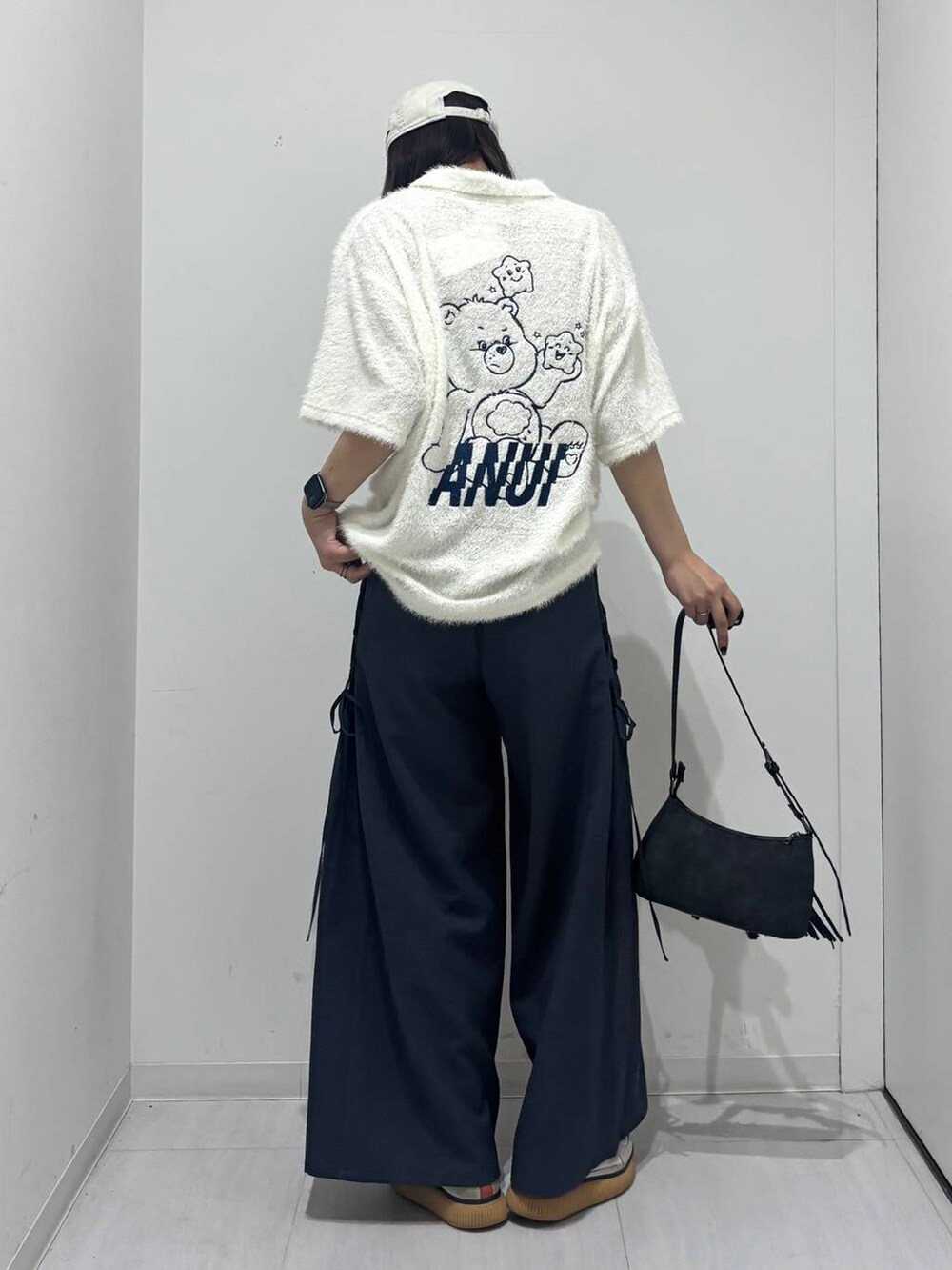 ブラック系のショルダーバッグ、グレー系のスラックス、ホワイト系のポロシャツを着用したレディースの春コーディネートの7枚目の写真