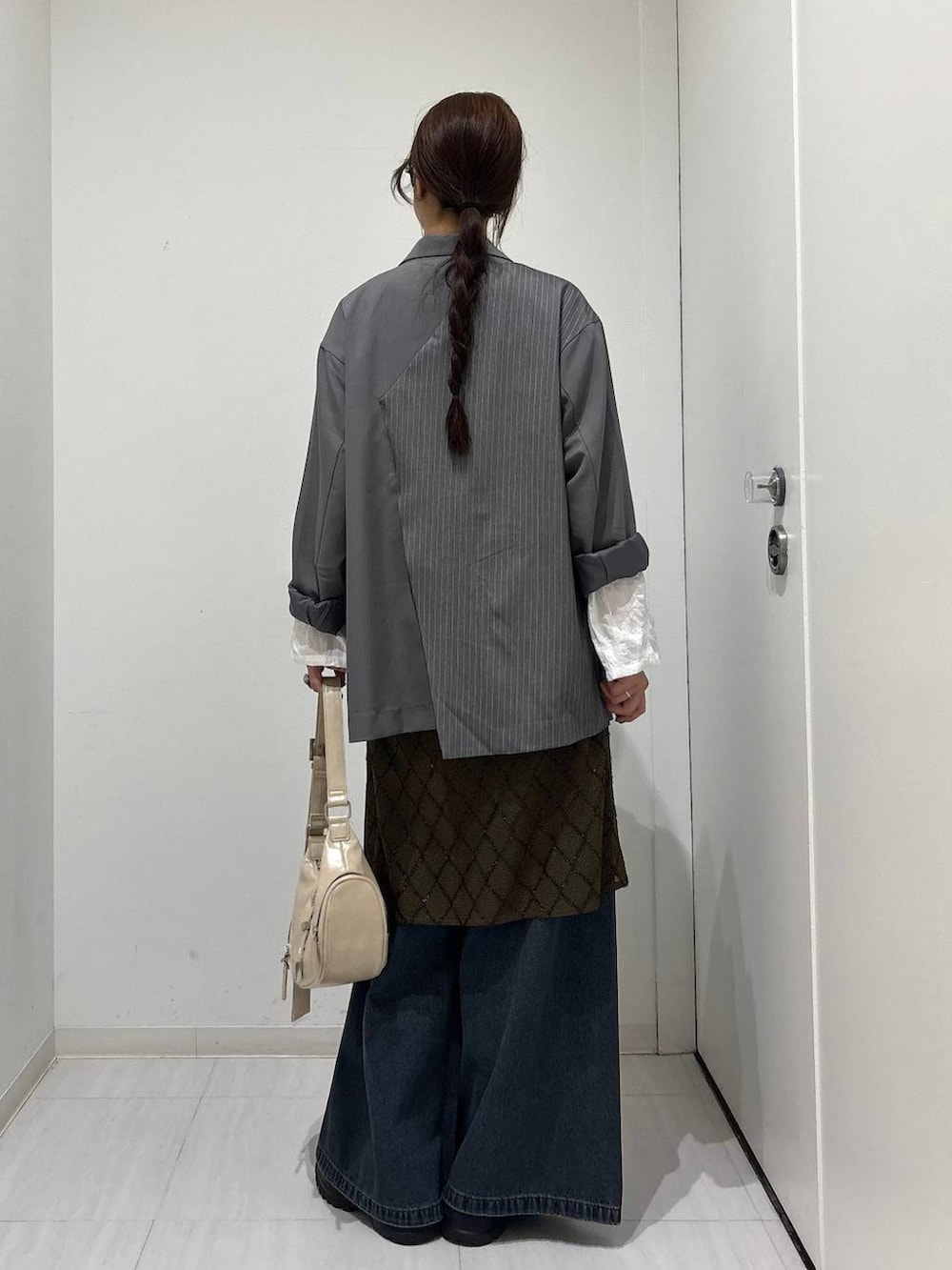 ブルー系のデニムパンツ、ブラック系のスニーカー、ホワイト系のショルダーバッグを着用したレディースの春コーディネートの6枚目の写真